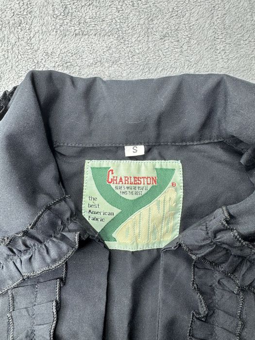 Чорна блузка з рюшами та зав'язками на талії.