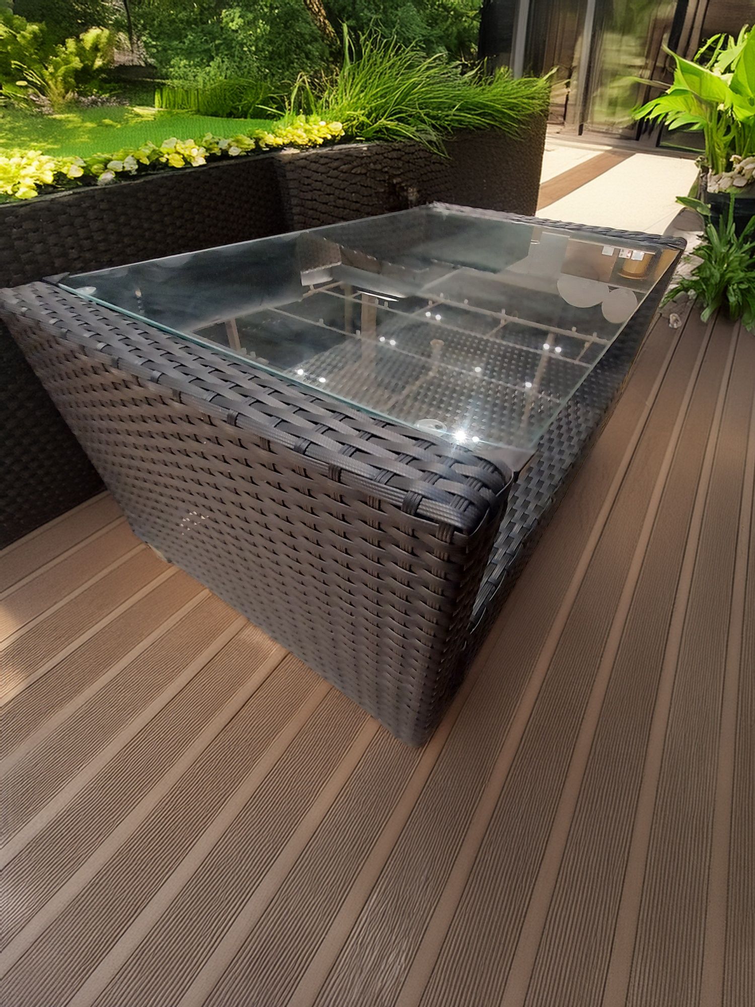 Meble ogrodowe sofa plus dwa fotele i stolik z drewnianym blatem.