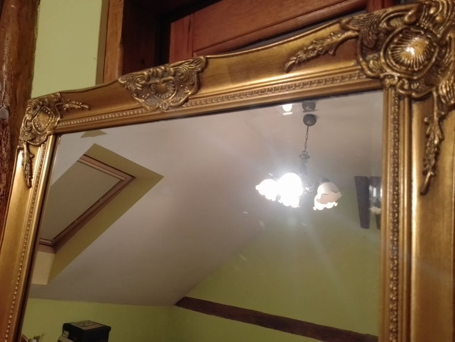 Duże lustro fazowane zdobione prostokątne w złotej ramie.