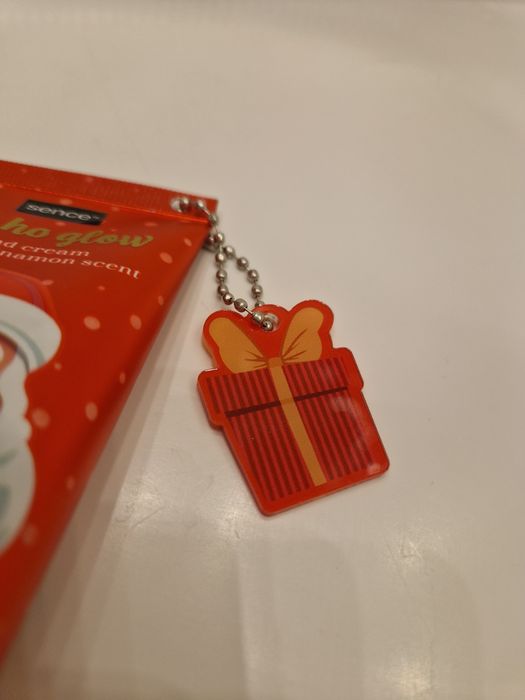 Cynamonowy krem do rąk Sence z breloczkiem w kształcie prezentu.