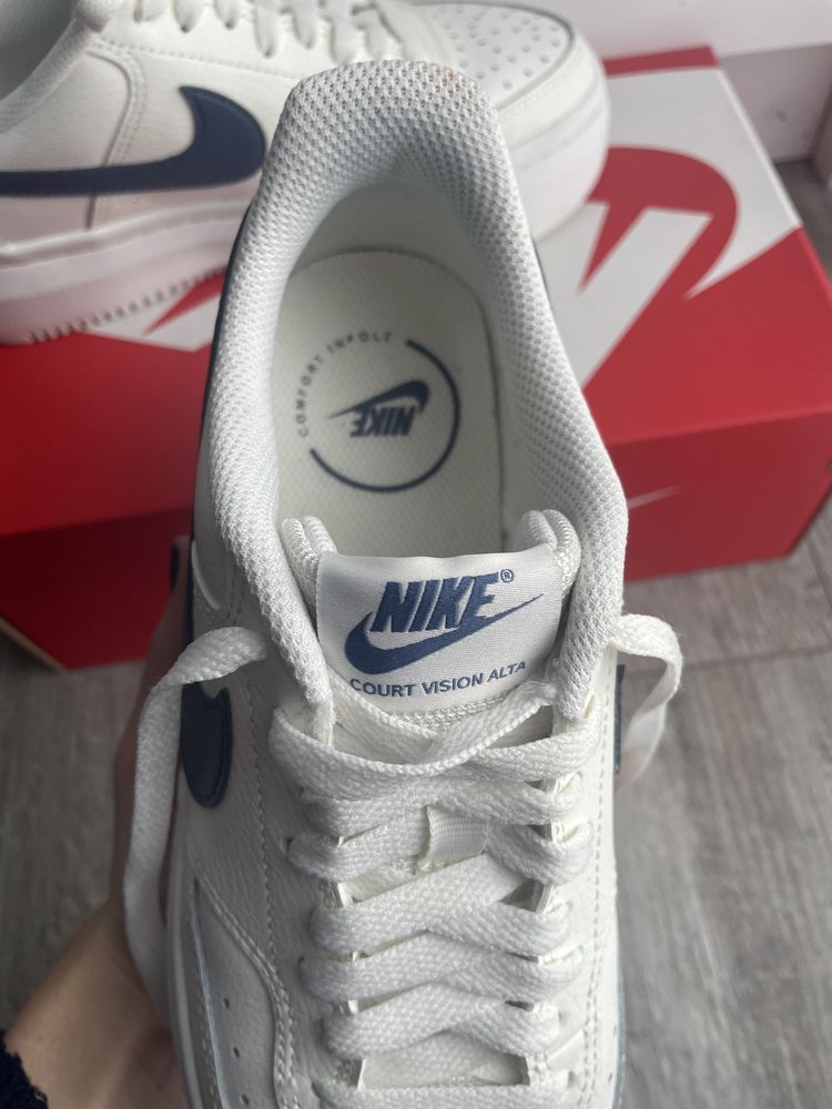 Białe buty Nike z niebieskim znaczkiem