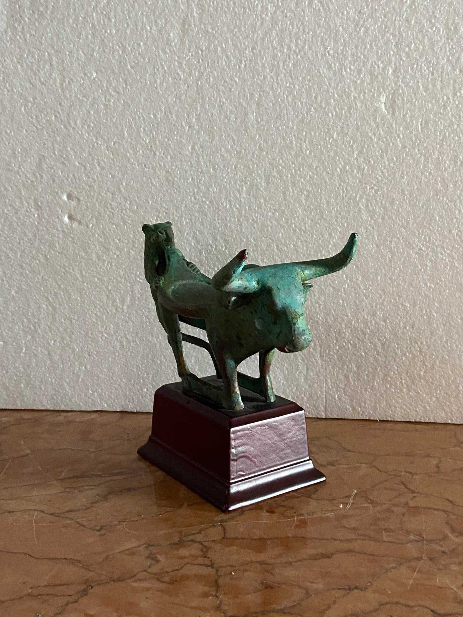 Pequena estatueta antiga de touro sendo atacado por felino