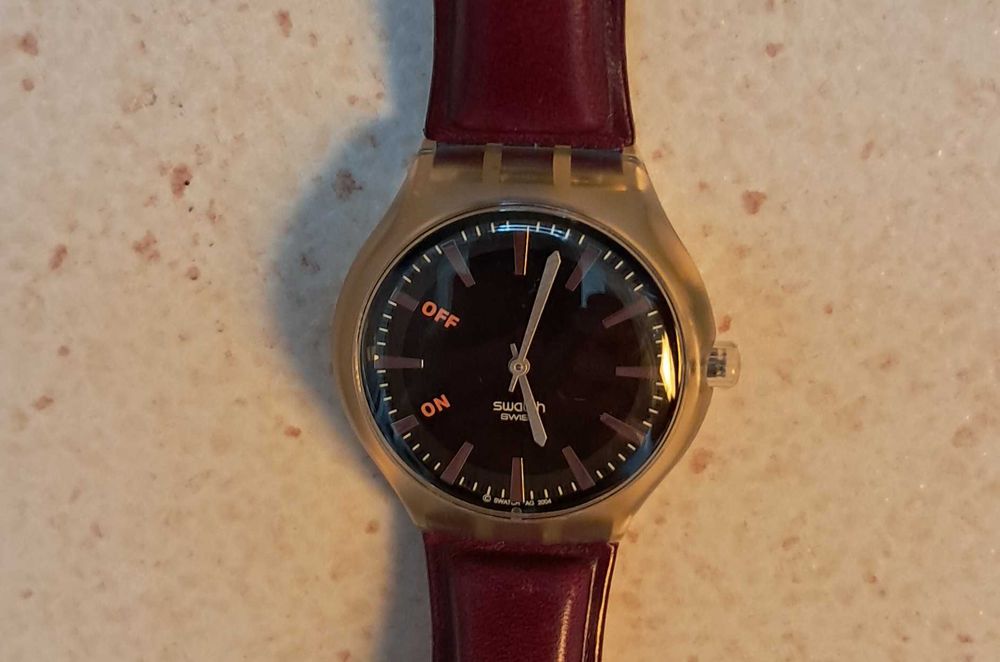 Relógio Swatch com fundo preto e bracelete pele castanha, impecável