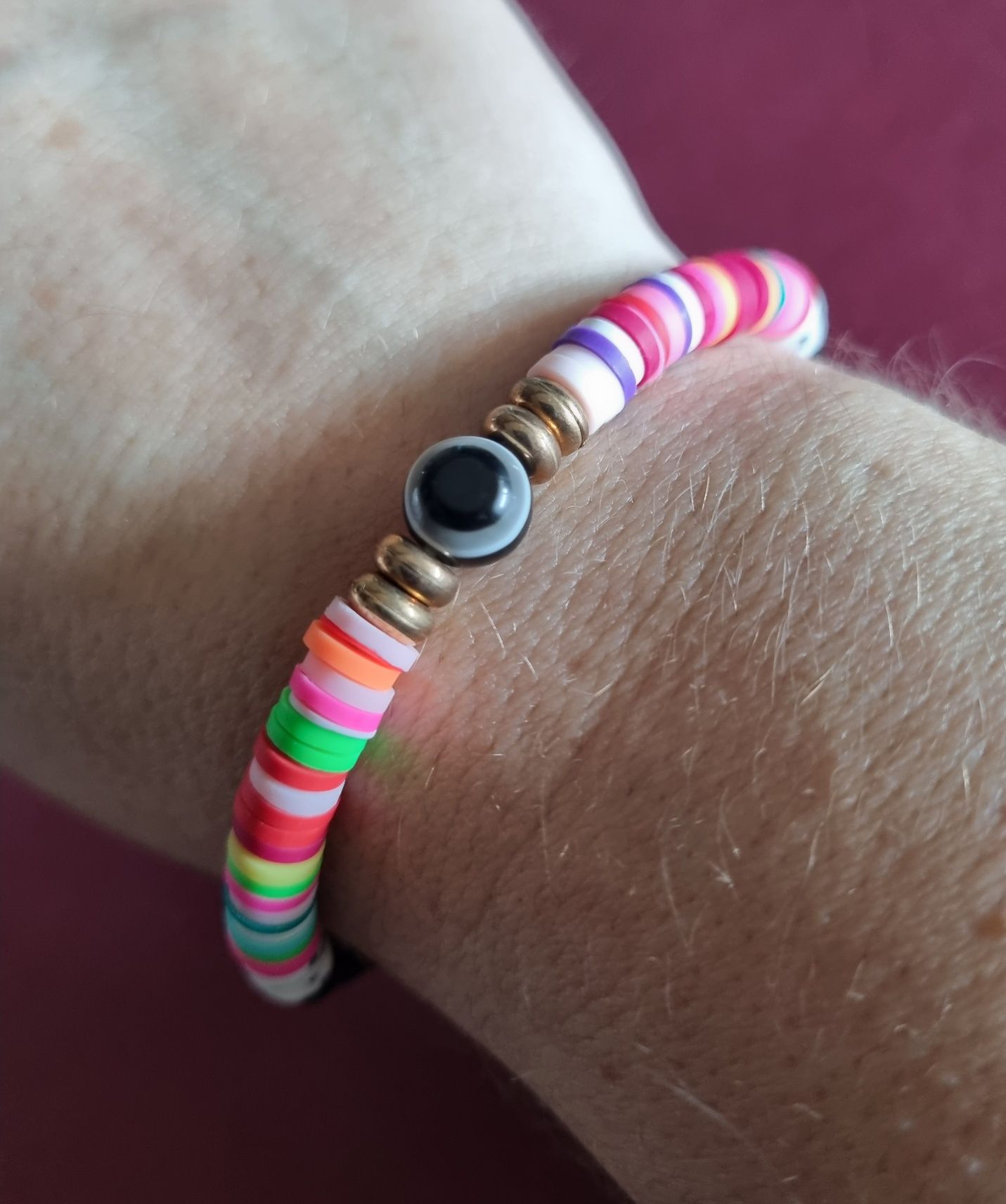 Pulseira elástica em tons de preto e multicor. Com olho de proteção