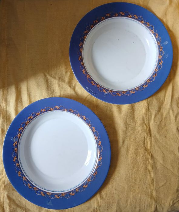 Dois pratos decorativos com borda azul e detalhes em laranja