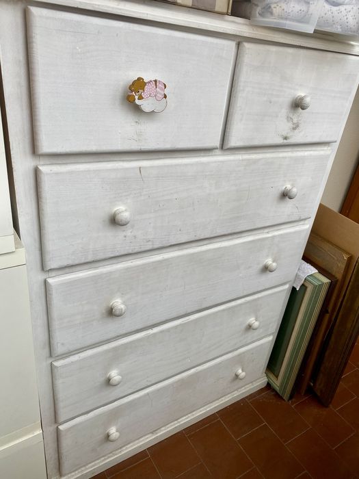 Comoda em pinho pintada de branco com gavetas forradas de rosa.