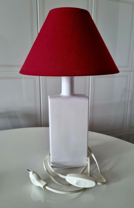 Candeeiro de mesa, feito com uma garrafa branca e abajour vermelho.