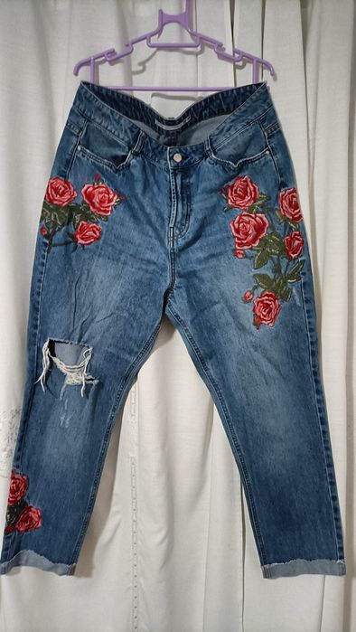 Calças de ganga para senhora com padrões de rosas vermelhas.