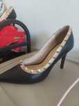 Sapatos de salto agulha pretos com tachas douradas.