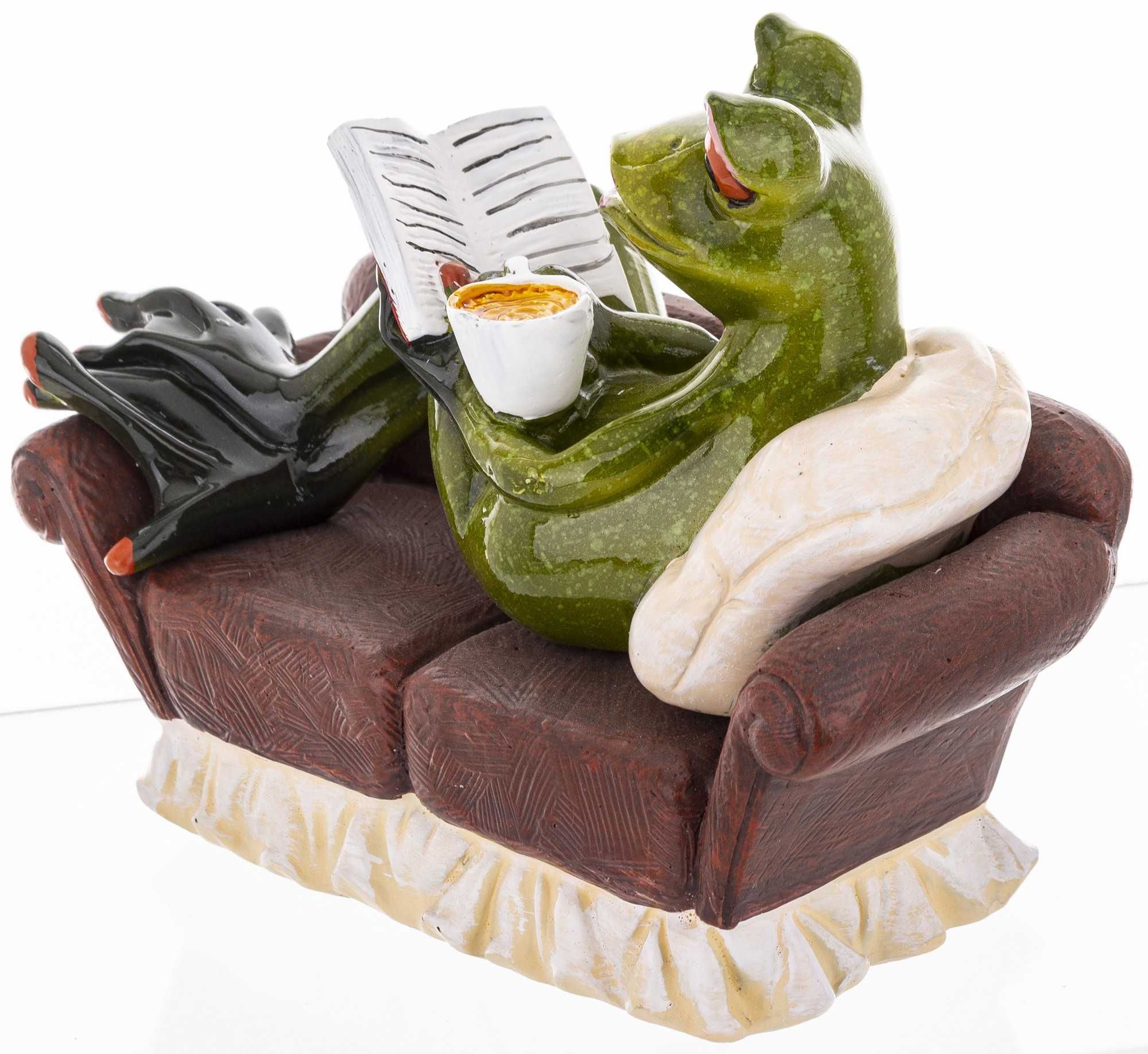 Figurka żaba na kanapie z kawą i książką
