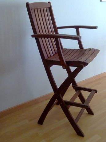 Cadeira de madeira alta com braços e com suporte para pés.