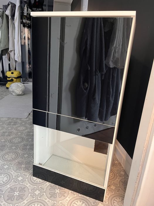 Szary dywan shaggy i szafka czarna wiszaca