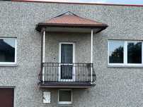 Balkon z zadaszeniem i balustradą kutą