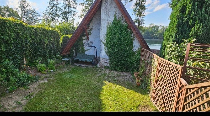 Domek nad jeziorem Rzuno z linią brzegową, łódką, kajakiem