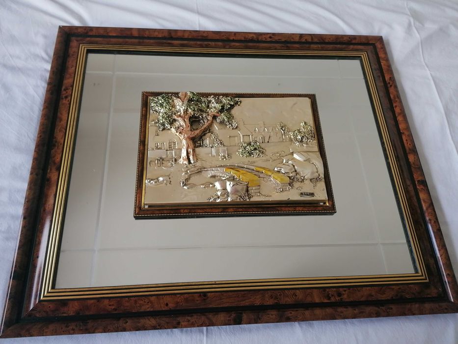 Quadro com espelho e moldura decorativa no meio.