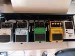 Vários pedais BOSS, transformador, pedalboard, cabos
