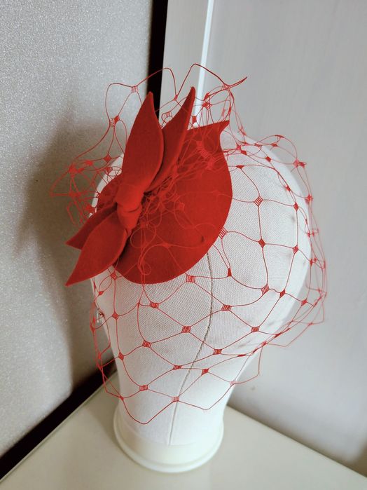 Małe piękne czerwony toczek z woalką. Czerwony mały fascynator woalką