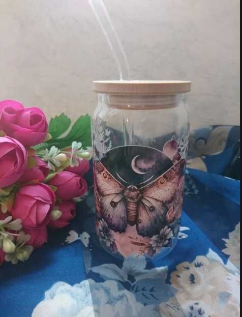 Szklana szklanka z drewnianą przykrywką i szklaną słomką, ćma, kwiaty
