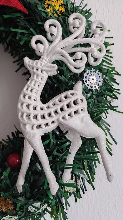 Wianek świąteczny na drzwi z czerwoną kokardą i białym reniferem