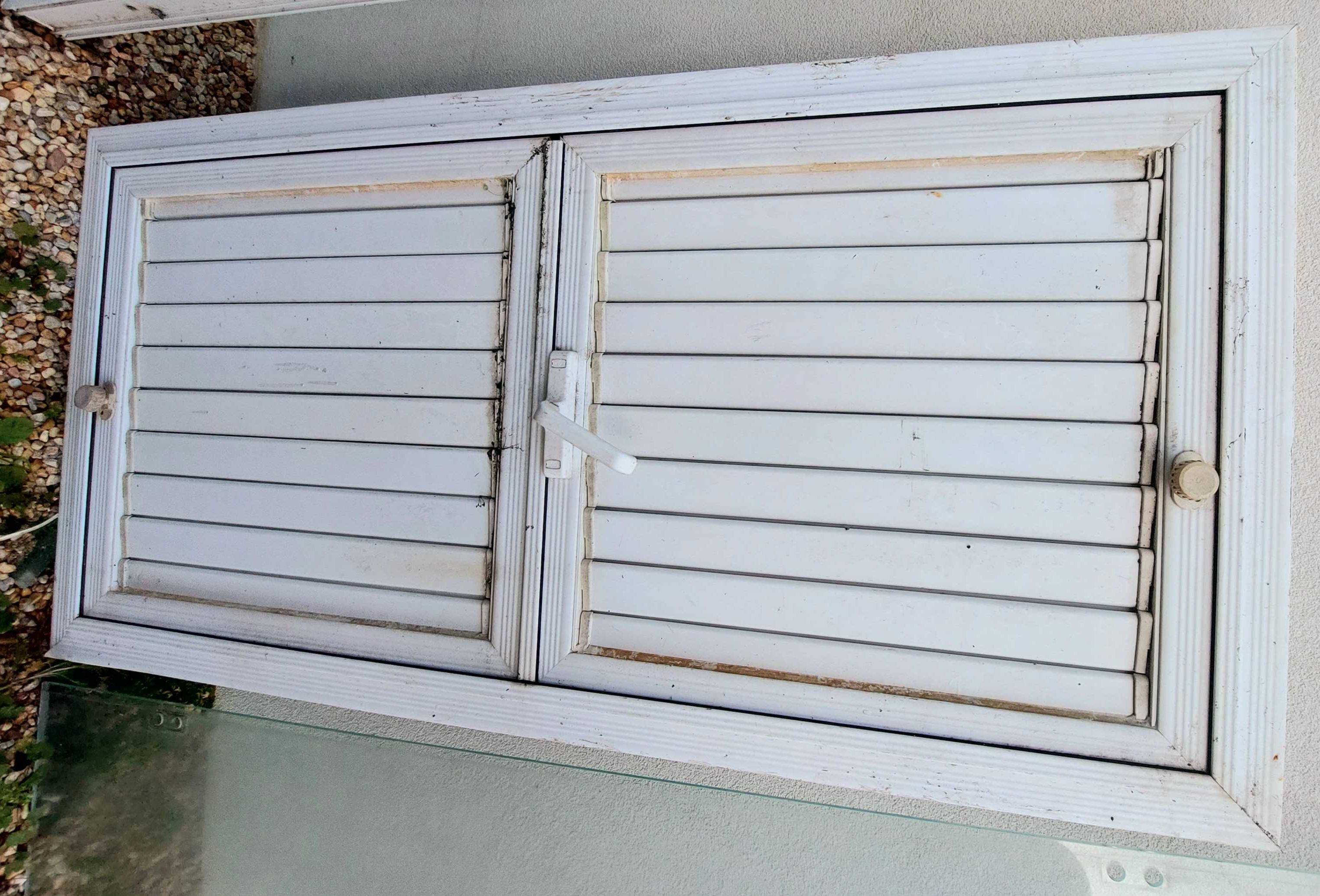 Janela em alumínio branco com lâminas orientáveis