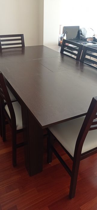 Mesa de madeira castanho escuro com seis cadeiras de pele