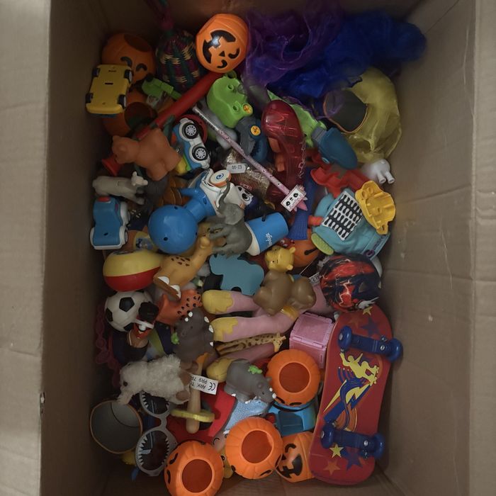 На изображении показана коробка, наполненная разнообразными игрушками.