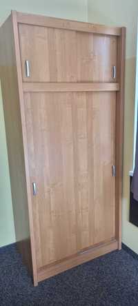 Szafa dwudrzwiowa z odsuwanymi drzwiami w kolorze drewna.