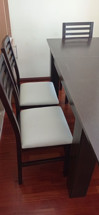 Mesa de madeira castanho escuro com seis cadeiras de pele