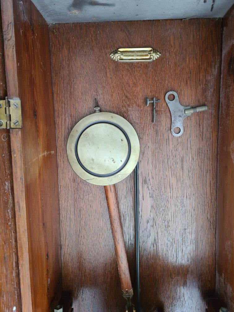 Stary zegar z wahadlem wiszacy w obudowie drewnianej