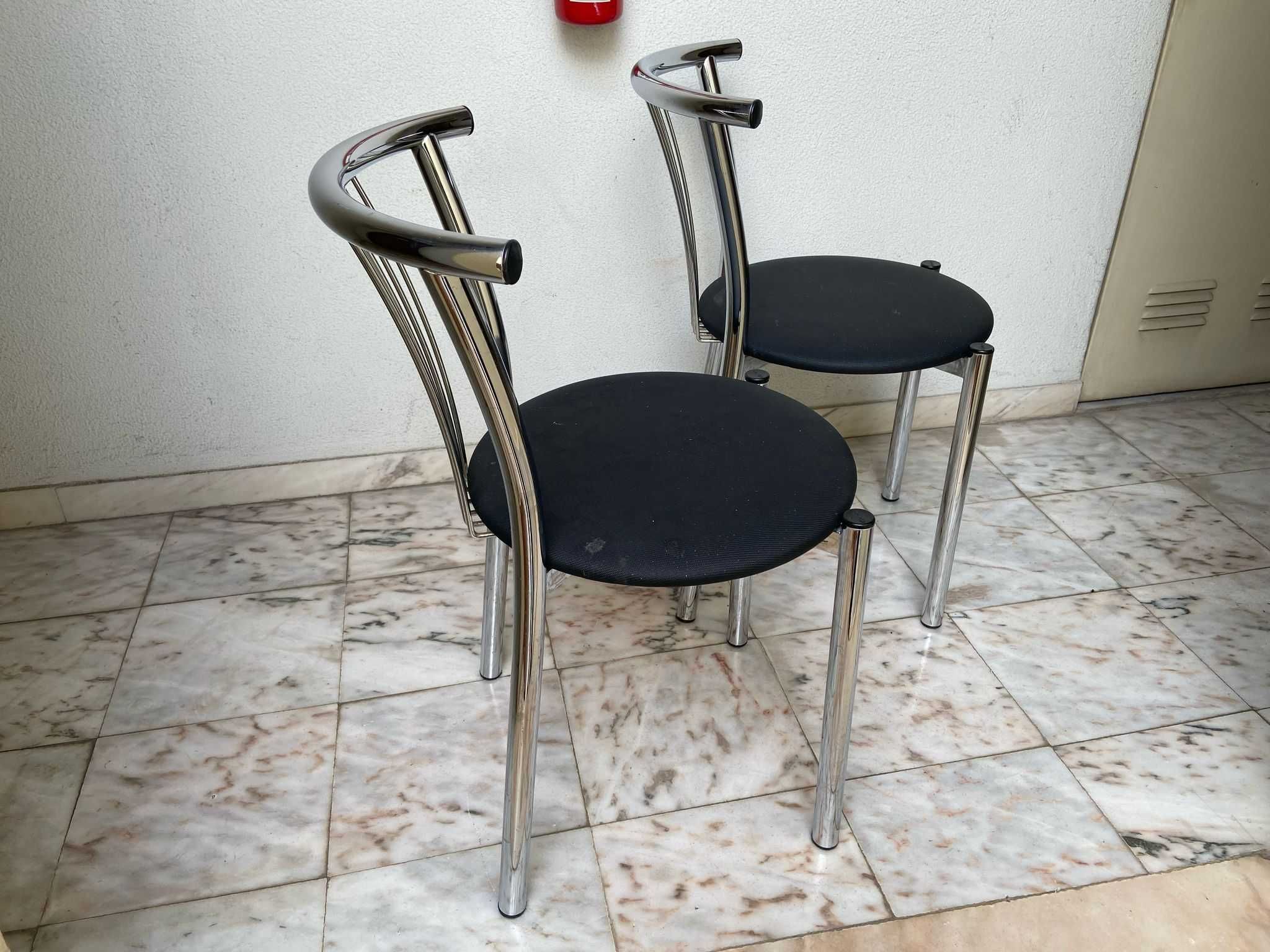 Duas cadeiras de metal, com tampo preto