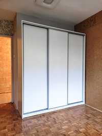 Biała szafa z drzwiami przesuwnymi szufladami półkami wieszakami