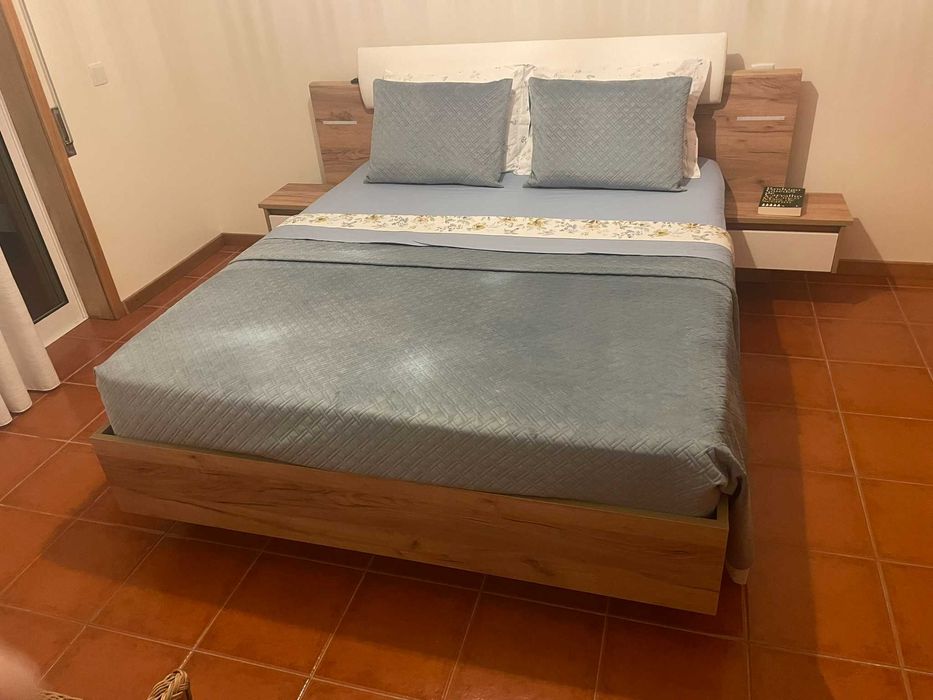 Cama de casal com mesas de cabeceira e iluminação