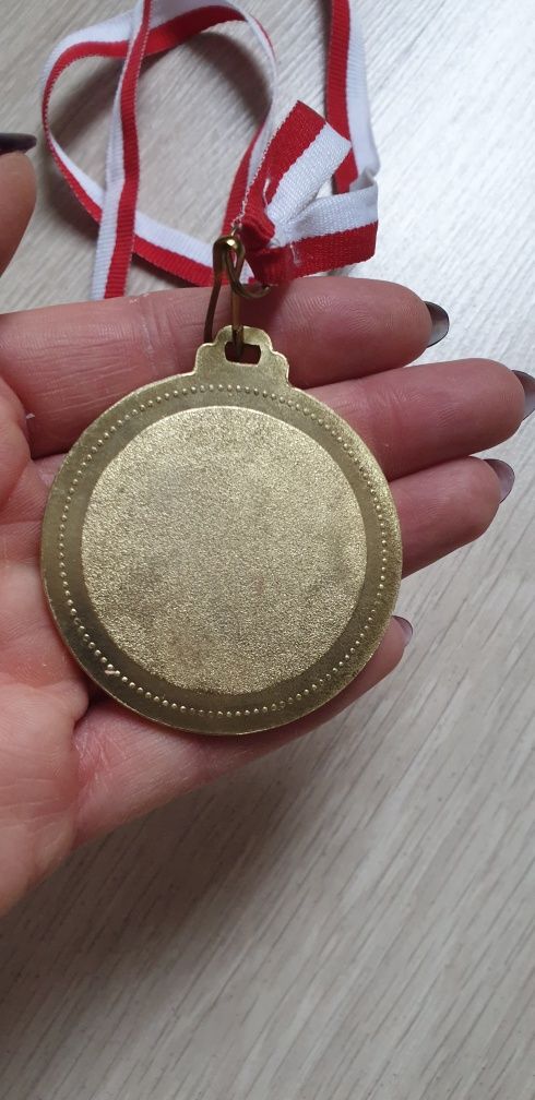 Medal w kolorze złotym na taśmie biało czarwonej