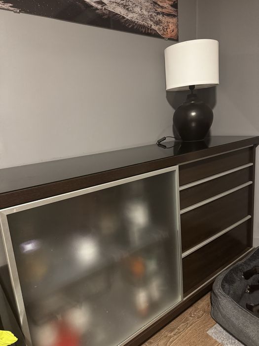 Czarna komoda z szufladami, szklany blat.