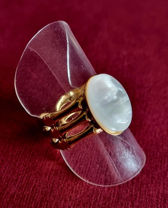 Anel dourado, em aço, com uma madrepérola oval.  Ajustável