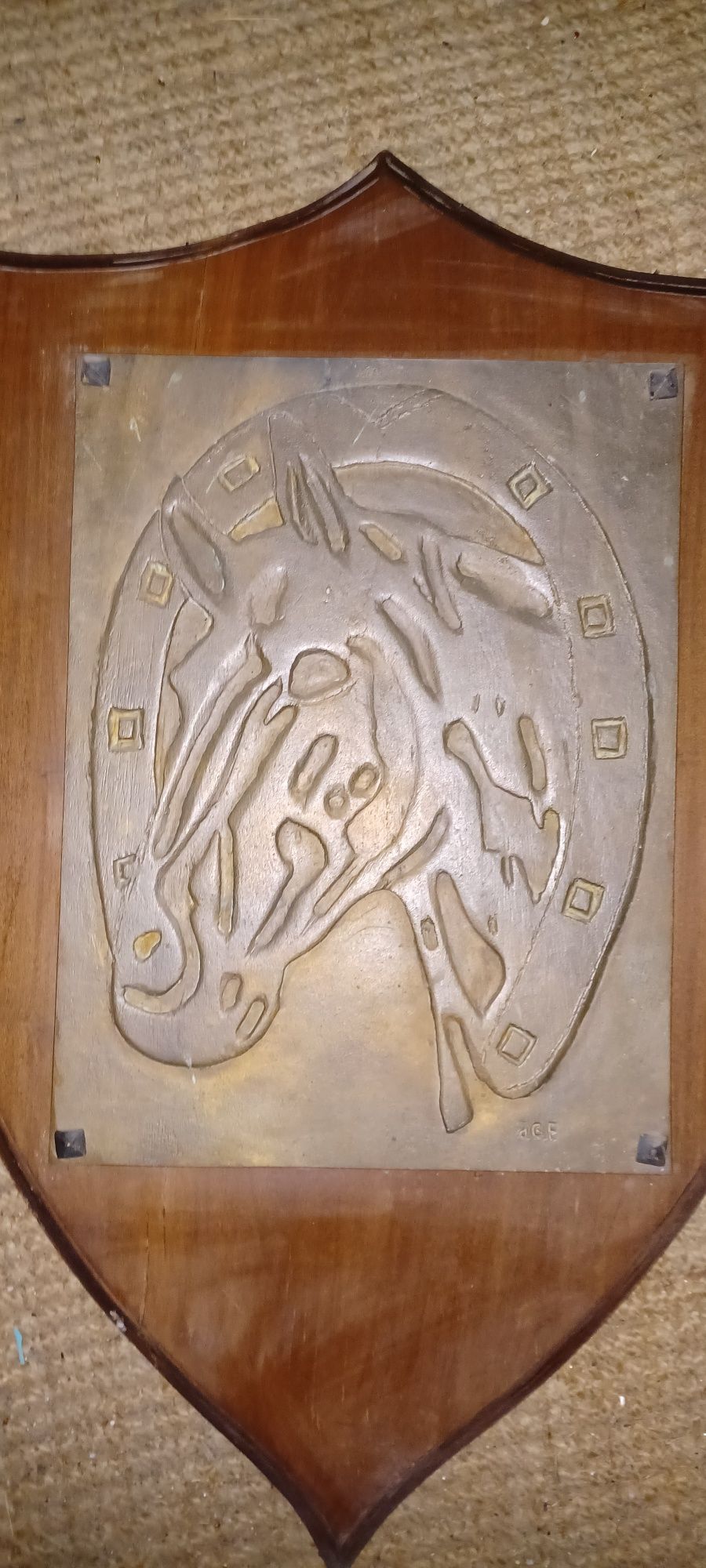 Placa de madeira em formato de escudo com cabeça de cavalo em placa de