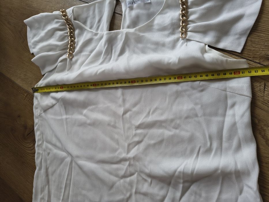 Elegancka ecru bluzka ze złotymi łańcuszkami falbany na ramionach