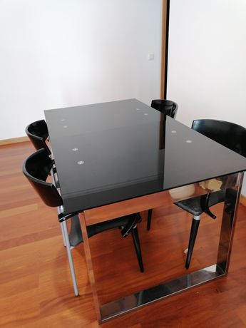 Mesa de jantar com tampo de vidro preto e 4 cadeiras.