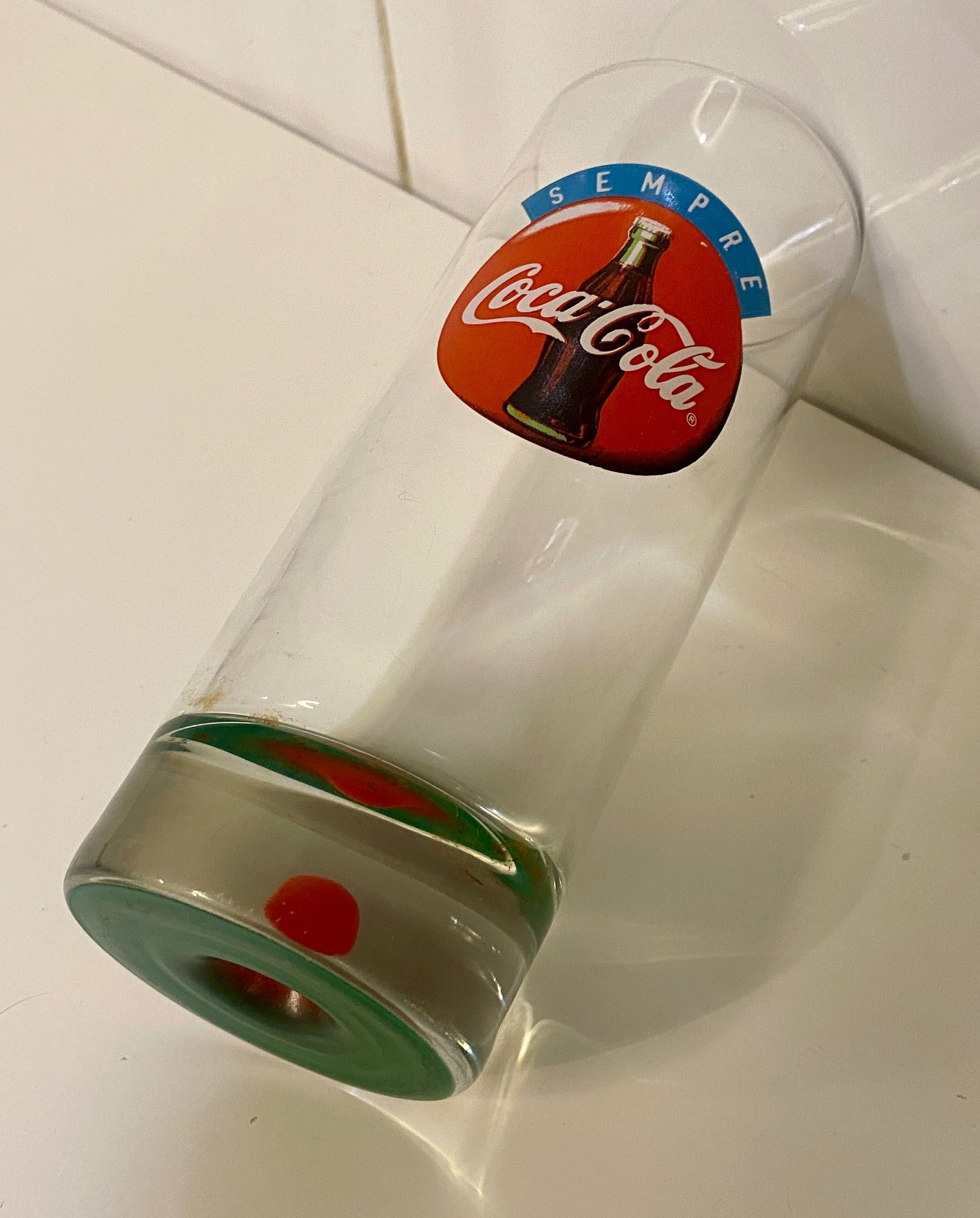 Copo antigo coca cola com relevo mama no fundo.