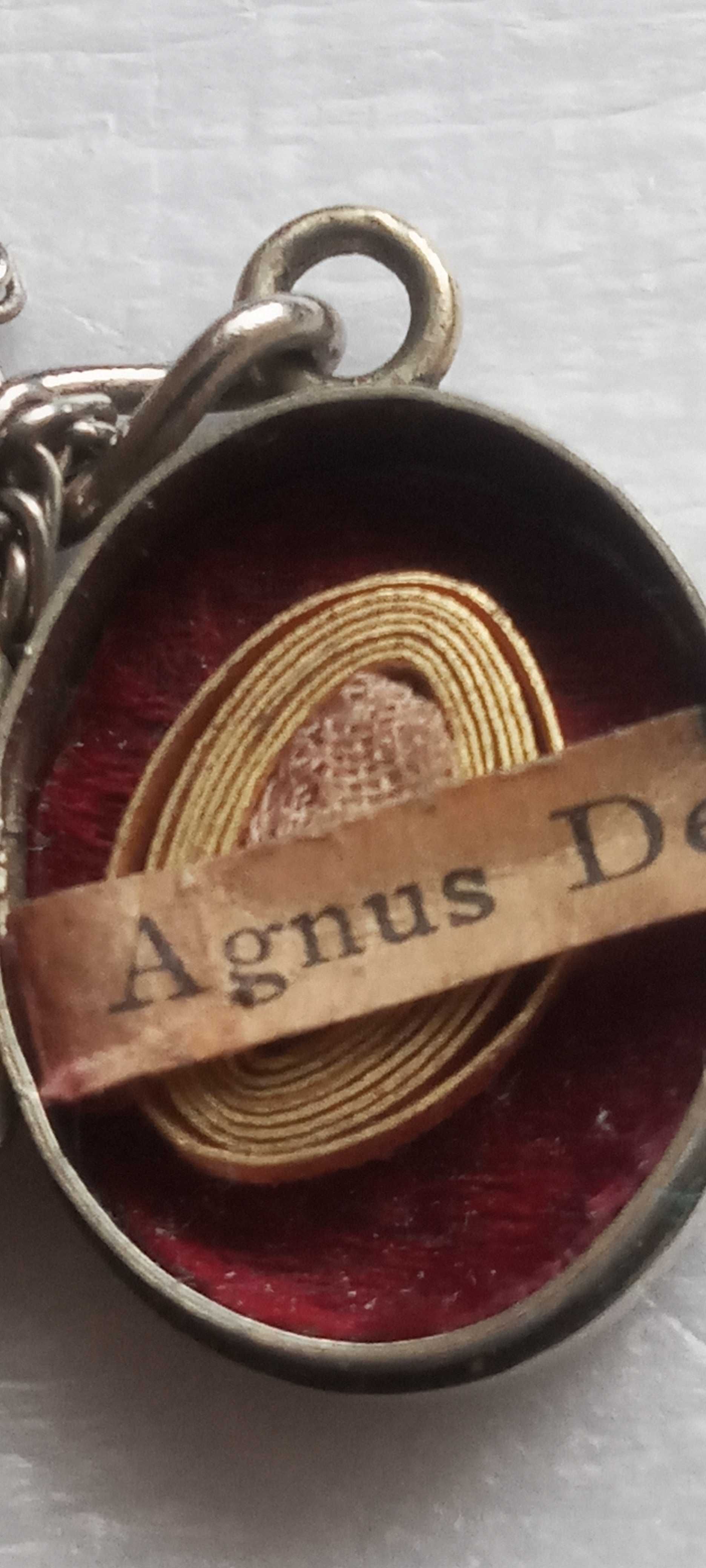 Stary, srebrny relikwiarz na łańcuszku Agnus Dei.