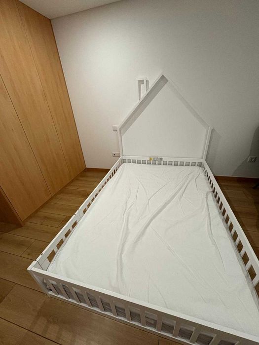 Cama de criança, com gradeamento e uma porta lateral.