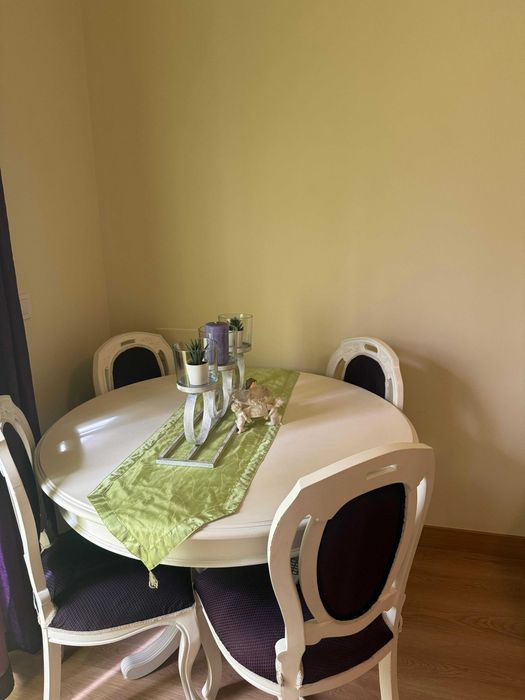 Mesa lacada de branco com quatro cadeiras forradas em tom roxo