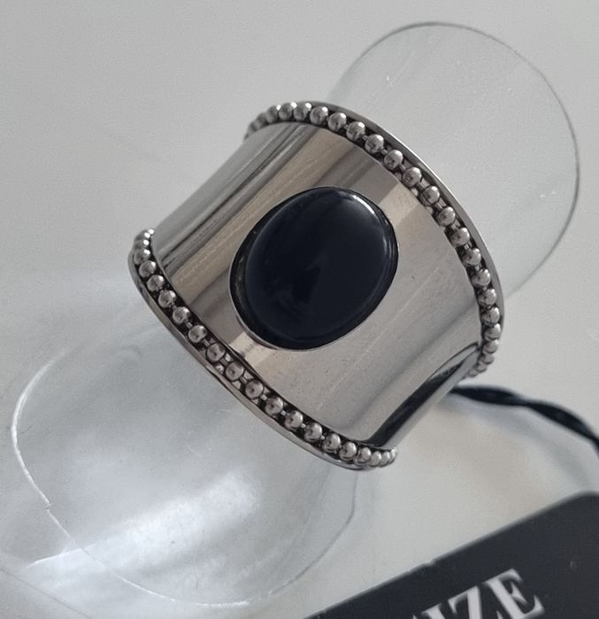 Anel prateado, em aço  com pedra preta oval. Ajustável