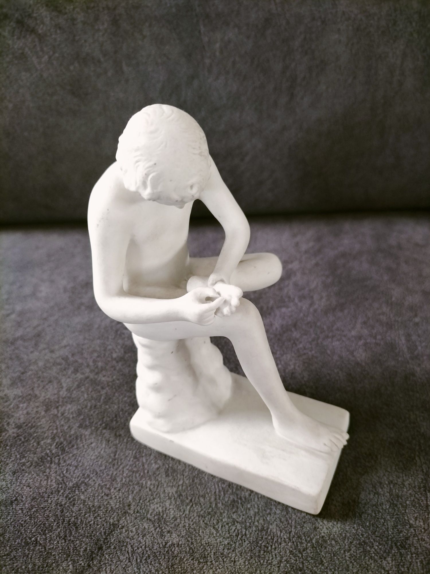 Porcelanowa figurka spinelio chłopiec z kolcem.