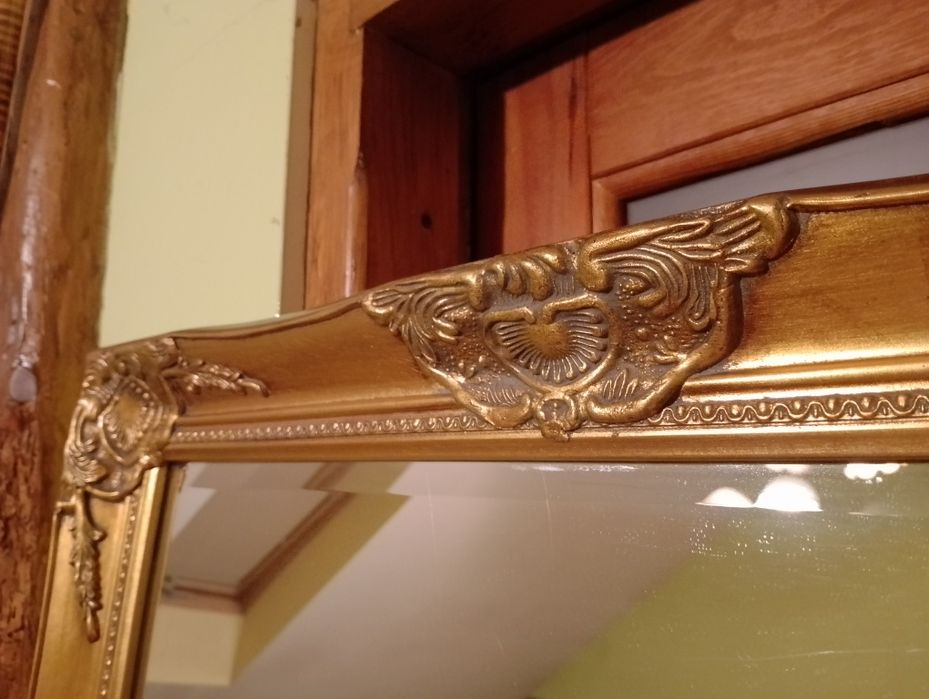 Duże lustro fazowane zdobione prostokątne w złotej ramie.