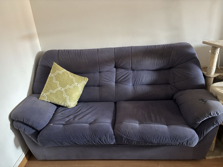 Sofá de sala, azul, com alguns anos e marcas de uso.