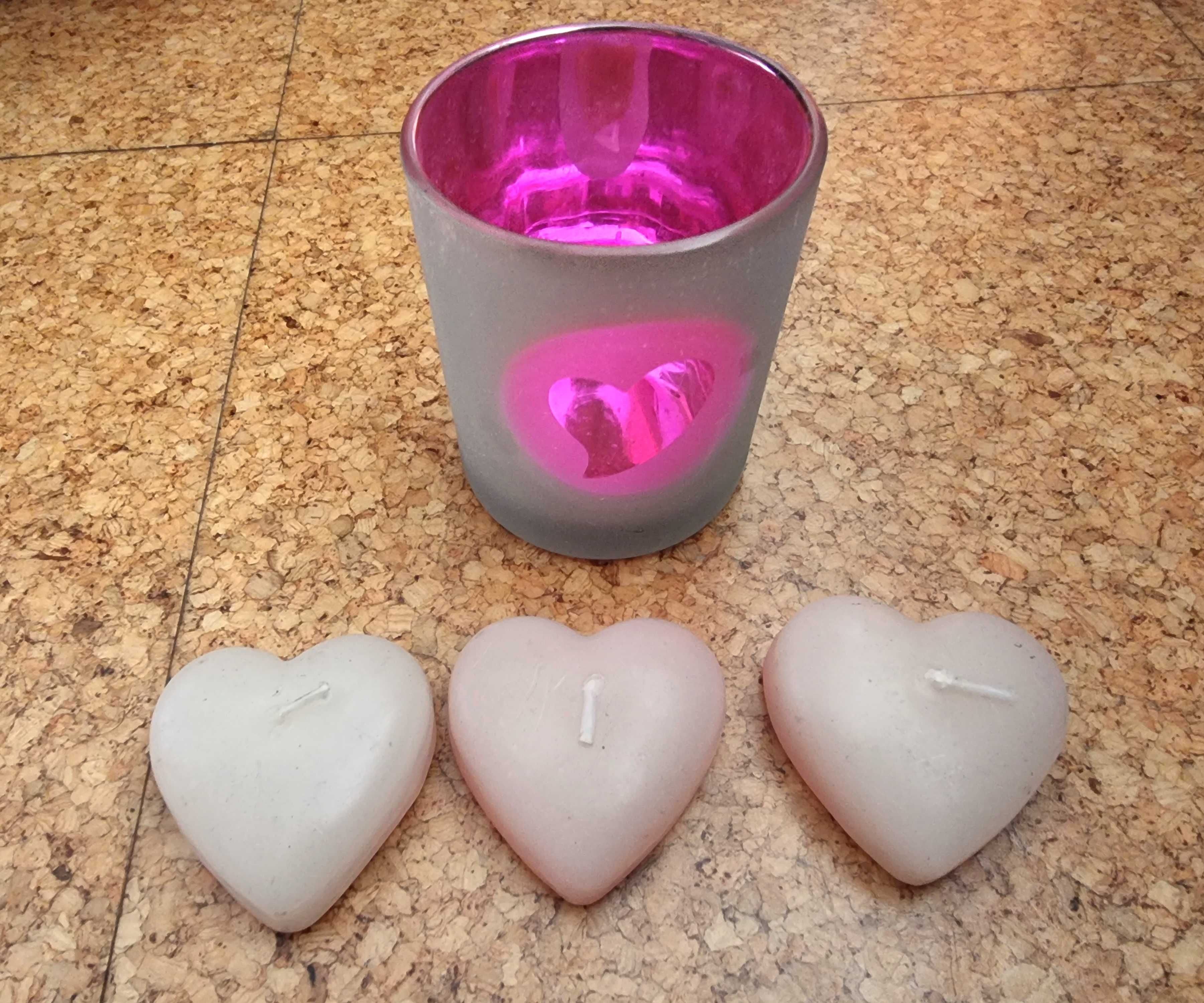 Copo em tons de rosa com três velas em formato de coração