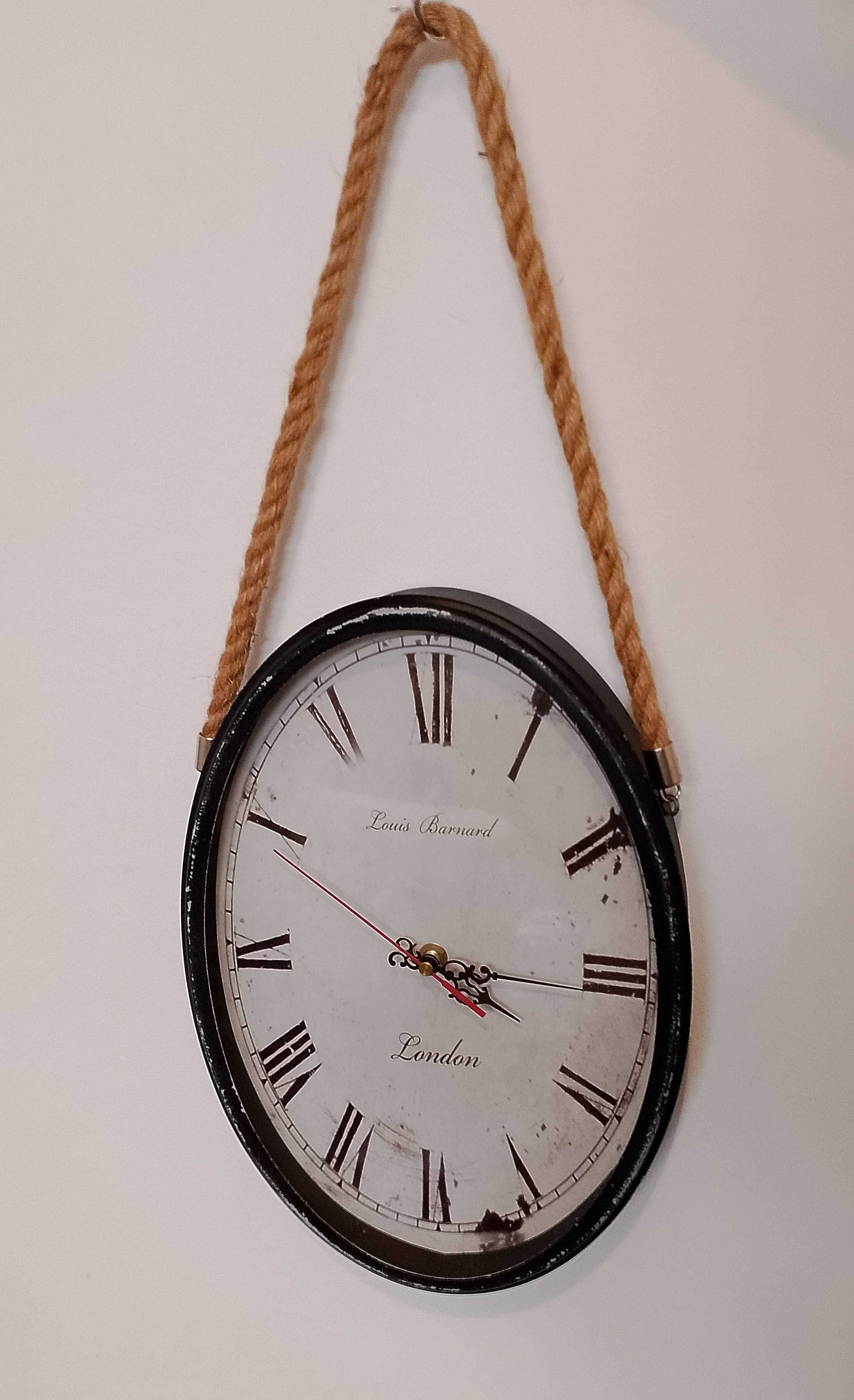 Duży zegar ścienny, wiszący na sznurze, styl vintage.