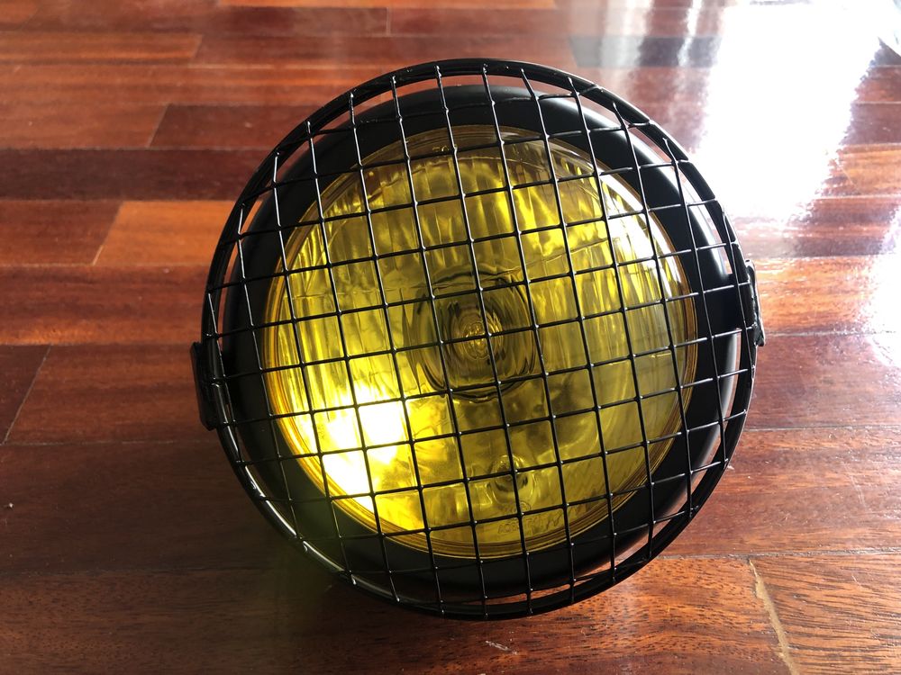 Farol frontal amarelo com grelha metálica dois apoios cafe racer