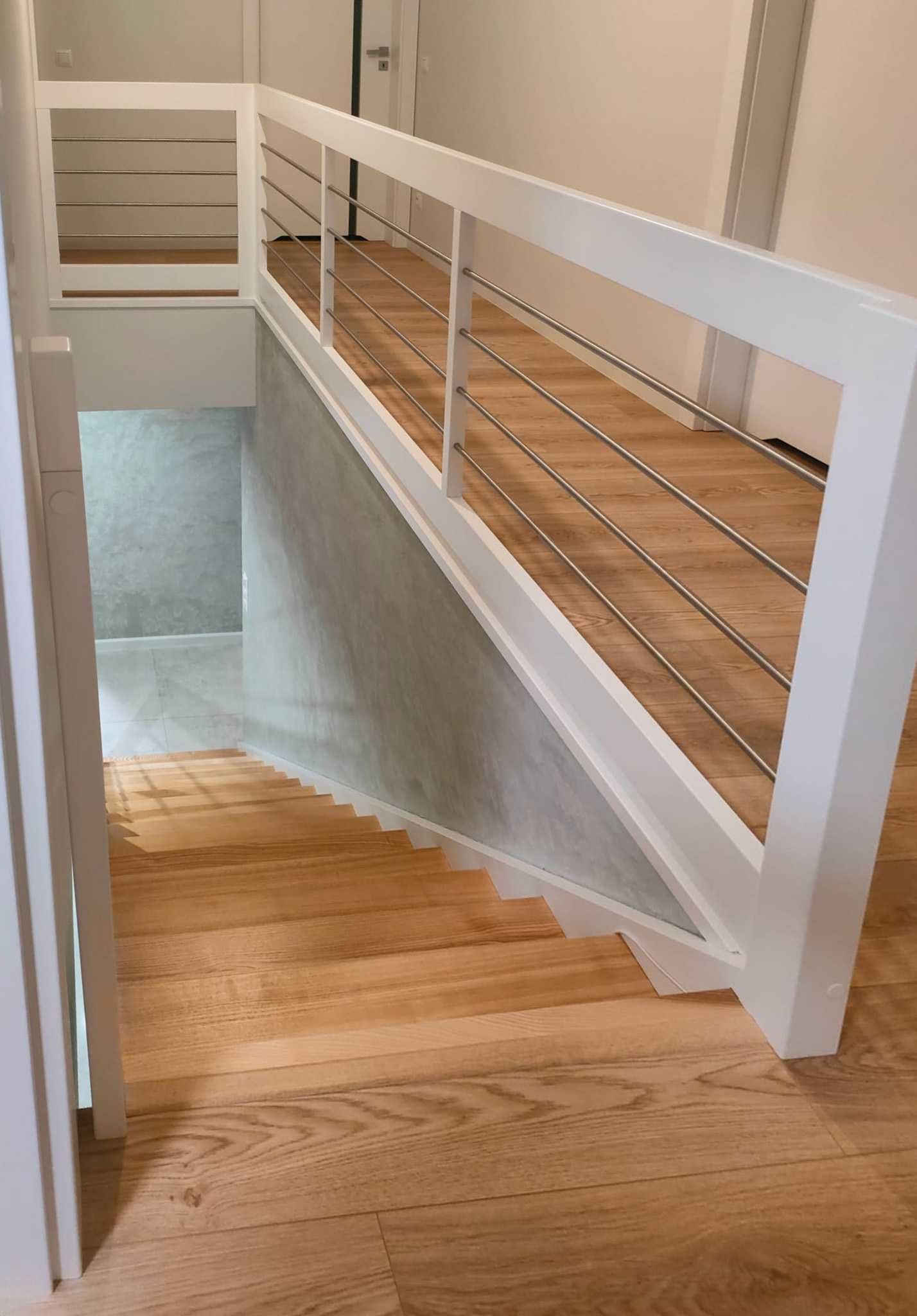 Białe proste schody drewniane z metalowymi relingami